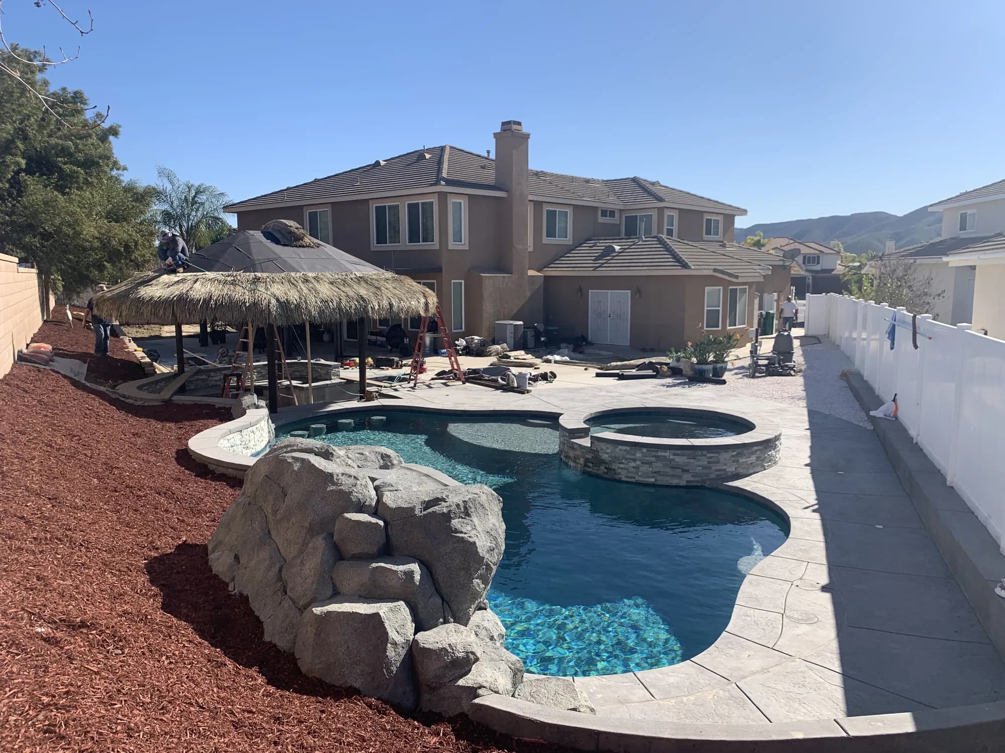 Freeform pool with a round spa, rock waterfall, and shaded poolside pavilion
