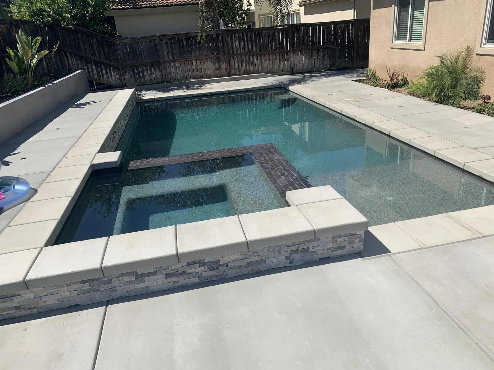 Rectangular pool with an integrated square spa and a contrasting tile detail